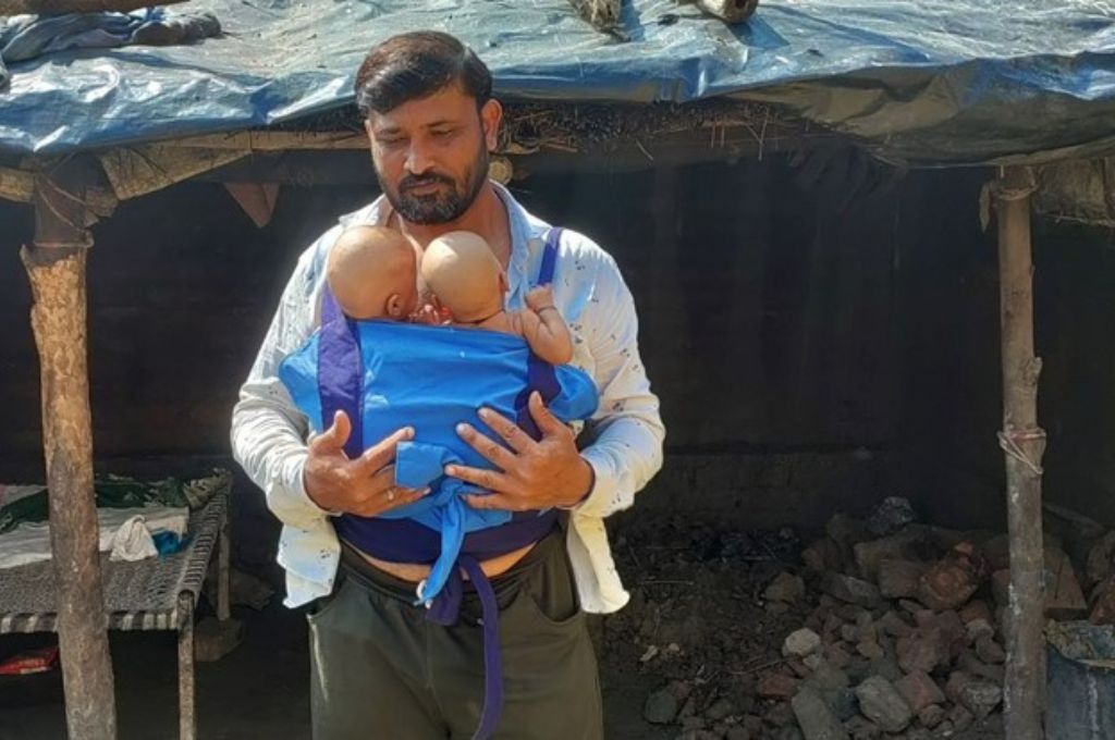 एक पिता अपने दो नवजात शिशुओं को हाथों में लिए हुए है-पिता