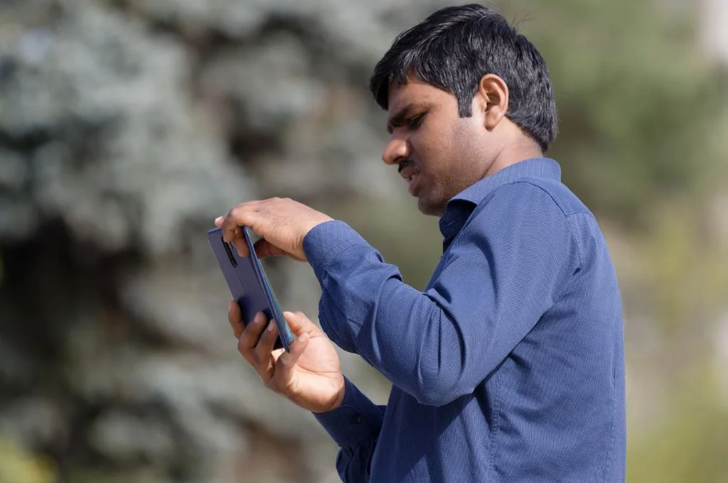 फोन की स्क्रीन देखता हुआ एक आदमी_नीति-निर्माता समाजसेवी संस्था