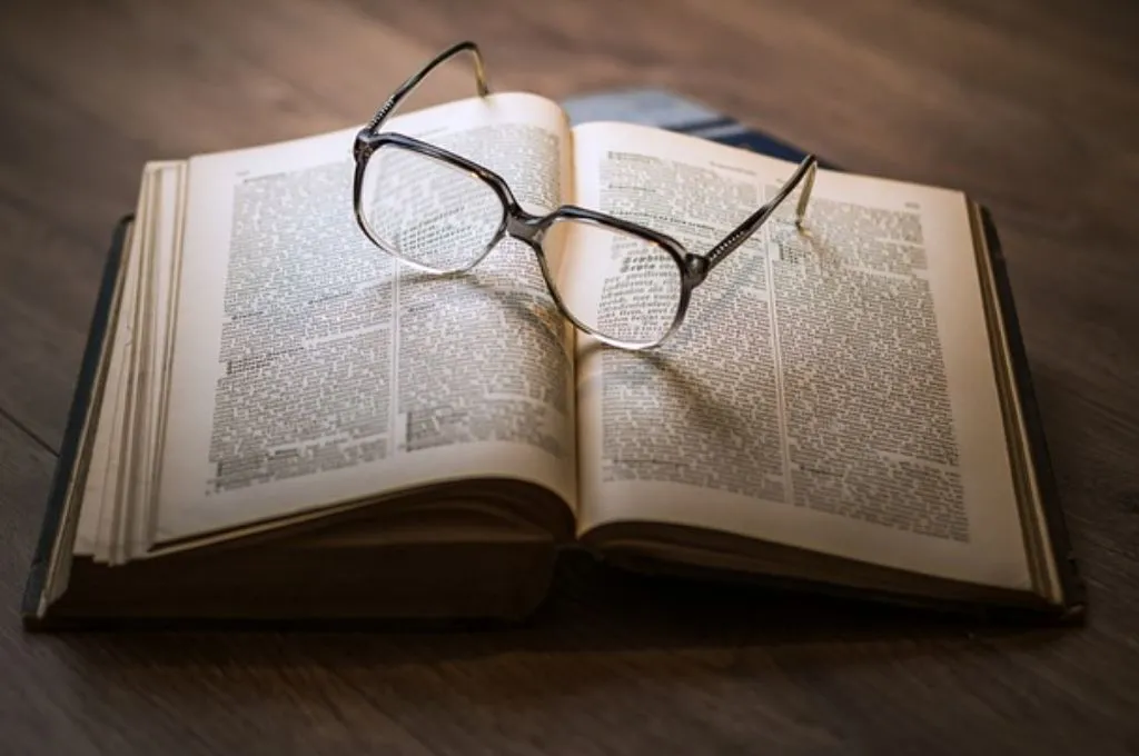 चश्मे के साथ रखी खुली हुई किताब—दलित साहित्य