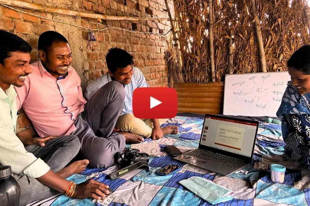 ग्रामीण परिवेश में लैपटॉप और व्हाइट बोर्ड पर गतिविधि कराते युवा पुरुष और महिला_समवेशी शिक्षा