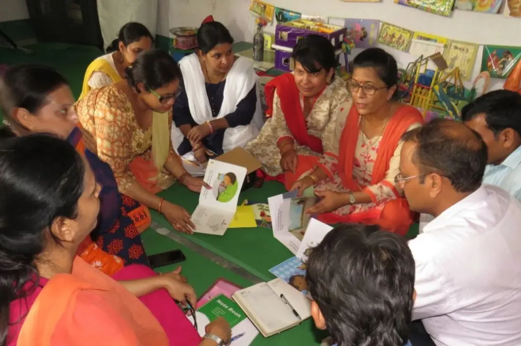 समूह में बैठे महिला एवं पुरुष किसी गतिविधि पर चर्चा करते हुए_शिक्षक