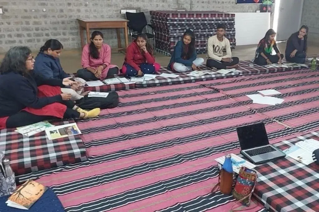 कमरे में बैठकर समूह में किसी विषय पर चर्चा करते हुए युवा—शिक्षा से आत्मनिर्भरता